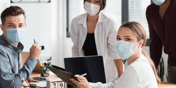 a bizhealth consultant showing her paper board to workplace employees at her desk